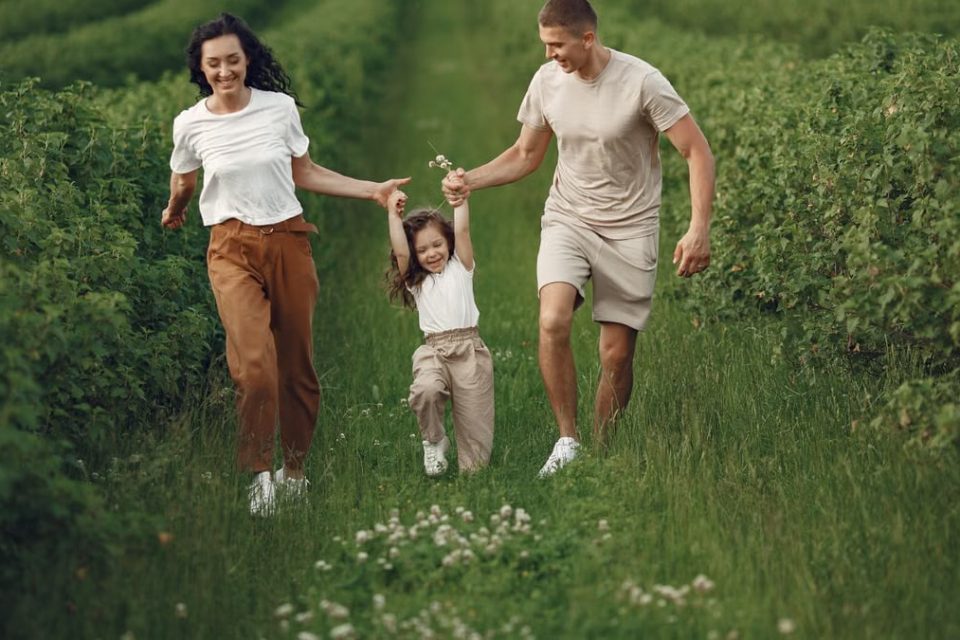 Joyful family enjoying a fun day outdoors in a green field, epitomizing togetherness and happiness.